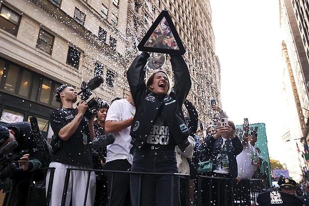 New York Liberty guard Sabrina Ionescu holds up the WNBA basketball championship trophy while riding down Broadway during a parade celebrating the team’s season championship, Thursday, Oct. 24, in New York.