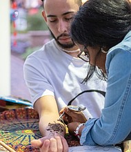 Henna artist Shikha Gupta applies a tattoo on Windell Camacho.