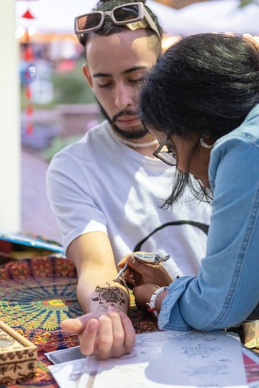 Henna artist Shikha Gupta applies a tattoo on Windell Camacho.