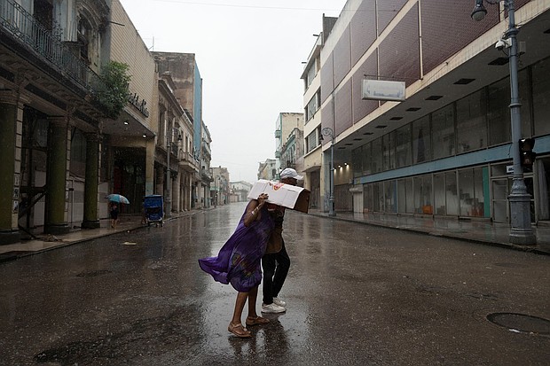People walk on a street as Hurricane Rafael passes over Havana on Wednesday.
Mandatory Credit:	Alexandre Meneghini/Reuters via CNN Newsource