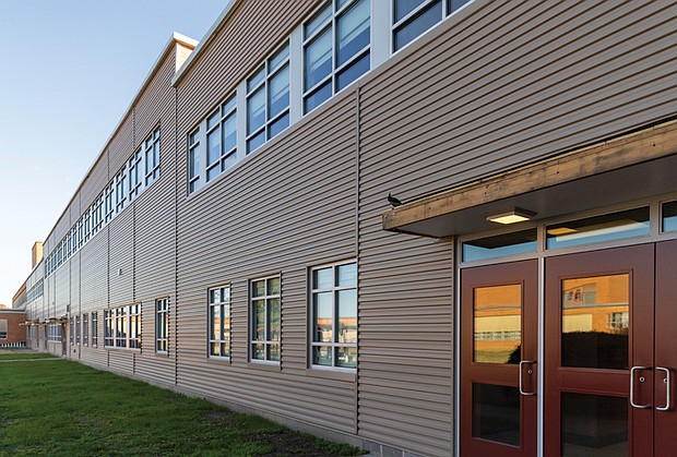 The reconstructed courtyard wall at John Marshall High School features new metal siding and windows, part of a project to address asbestos and other structural issues.