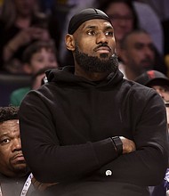 Los Angeles Lakers forward LeBron James watches from the bench during the first half of Sunday's game against the Portland Trail Blazers.
Mandatory Credit:	Etienne Laurent/AP via CNN Newsource