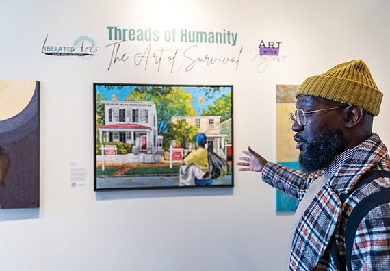 David Marion, visual artist and co-founder of the Liberated Arts Foundation, discusses one of his pieces in the pop-up exhibition “Threads of Humanity: The Art of Survival” at the Black History Museum & Cultural Center of Virginia. Curated by Marion and his wife, Tiara Green, the exhibit focuses on homelessness, with a portion of art sales supporting organizations that aid unhoused individuals.