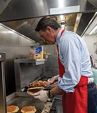Gov. Glenn Youngkin prepares to serve pancakes to guests Dec. 16 at McLean’s Restaurant, following the announcement of a proposal to eliminate taxes on tipped income.