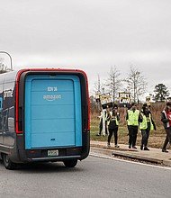 Amazon delivery trucks pass people holding signs and marching during a strike by Teamsters union members at an Amazon facility in Alpharetta, Georgia, on Thursday, December 19.
Mandatory Credit:	Elijah Nouvelage/Reuters via CNN Newsource