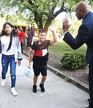 Delegate Michael J. Jones, former Richmond City Council member for the 9th District, greets students at G.H. Reid Elementary School with a high-five as they arrive for their first day of school on Aug. 19.