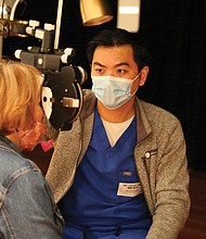 A volunteer at a recent health care event conducts an eye exam.