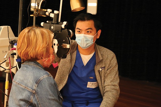 A volunteer at a recent health care event conducts an eye exam.