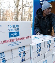 James Thomas (front) and Collin Owen (back) of Richmond City Parks and Recreation unload cases of 10-year shelf-life emergency drinking water at Pine Camp Community Center Jan. 7.