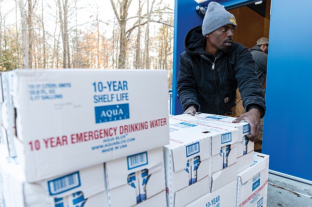 James Thomas (front) and Collin Owen (back) of Richmond City Parks and Recreation unload cases of 10-year shelf-life emergency drinking water at Pine Camp Community Center Jan. 7.