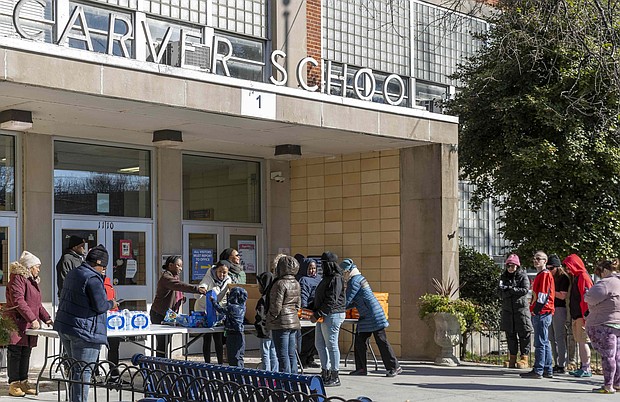 Families line up outside Carver Elementary School on Thursday, Jan. 9, to receive lunch and bottled water as part of Richmond Public Schools' effort to support the community during the ongoing water crisis.  Julianne Tripp Hillian/Richmond Free Press