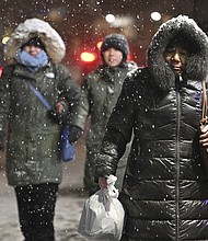 Pedestrians walk through falling snow in New York City Sunday.
Mandatory Credit:	Anthony Behar/Sipa USA/AP via CNN Newsource