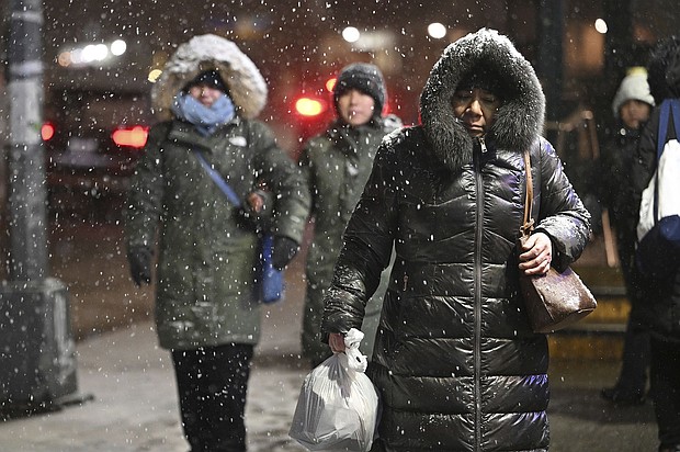 Pedestrians walk through falling snow in New York City Sunday.
Mandatory Credit:	Anthony Behar/Sipa USA/AP via CNN Newsource