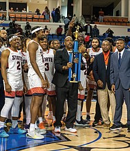 Virginia State Trojans celebrate their hard-fought 78-74 victory over Virginia Union in the Freedom Classic, hoisting the trophy as coaches, players, and cheerleaders share the moment of triumph.