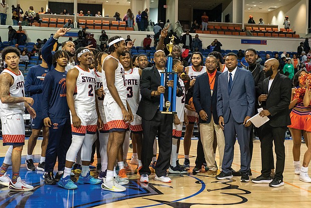 Virginia State Trojans celebrate their hard-fought 78-74 victory over Virginia Union in the Freedom Classic, hoisting the trophy as coaches, players, and cheerleaders share the moment of triumph.