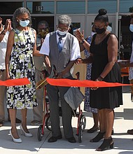 Henry L. Marsh III cuts the ribbon at a ceremony dedicating a Richmond elementary school named in his honor. Flanking Marsh are his daughter, Nadine Marsh-Carter, left and Principal Kimberly Cook.