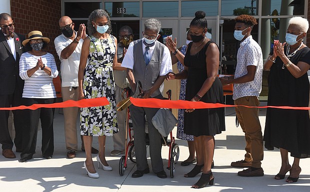 Henry L. Marsh III cuts the ribbon at a ceremony dedicating a Richmond elementary school named in his honor. Flanking Marsh are his daughter, Nadine Marsh-Carter, left and Principal Kimberly Cook.