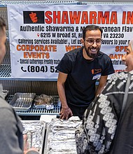 Bashar (left) and Hasan (right) greet customers at the Shawarma Inc. booth, where they serve a variety of authentic shawarma and Mediterranean foods.