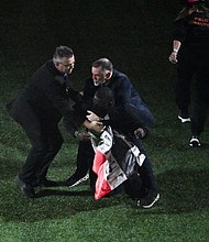 Security personnel grab the protester during Kendrick Lamar's performance.
Mandatory Credit:	Chandan Khanna/AFP/Getty Images via CNN Newsource