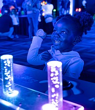 Sarai, 2, interacts with a glow-in-the-dark display at the Science Museum of Virginia.