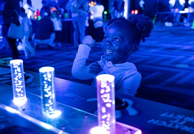 Sarai, 2, interacts with a glow-in-the-dark display at the Science Museum of Virginia.