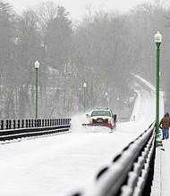 A snow plow clears the Nickel Bridge as two pedestrians walk the span on Feb. 19. The bridge was closed due to the winter weather.