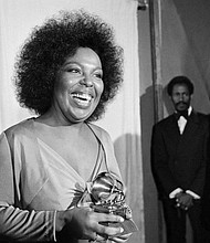 Roberta Flack holds the Grammy award for her record, “Killing Me Softly With His Song” as singer Isaac Hayes, right, looks on at the Grammy Awards in Los Angeles on March 4, 1974.