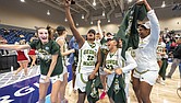 George Mason players celebrate after defeating Saint Joseph’s to win the 2025 Atlantic 10 Women’s Basketball Championship, posing with the official tournament sign in the Henrico Sports and Events Center.