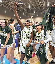 George Mason players celebrate after defeating Saint Joseph’s to win the 2025 Atlantic 10 Women’s Basketball Championship, posing with the official tournament sign in the Henrico Sports and Events Center.