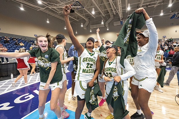 George Mason players celebrate after defeating Saint Joseph’s to win the 2025 Atlantic 10 Women’s Basketball Championship, posing with the official tournament sign in the Henrico Sports and Events Center.