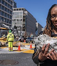 Tears roll down the face of Starlette Thomas, of Bowie, Md., as she holds a chunk of pavement from the Black Lives Matter plaza, Monday, March 10, as the mural begins to be demolished in Washington. “I needed to be here to bear witness,” says Thomas, who was present at the 2020 George Floyd protests.