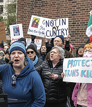 Organizer Kienan Chung stands beside Tess Evans as she speaks to hundreds of protesters at the Bell Tower in Capitol Square on Wednesday, Feb. 5.