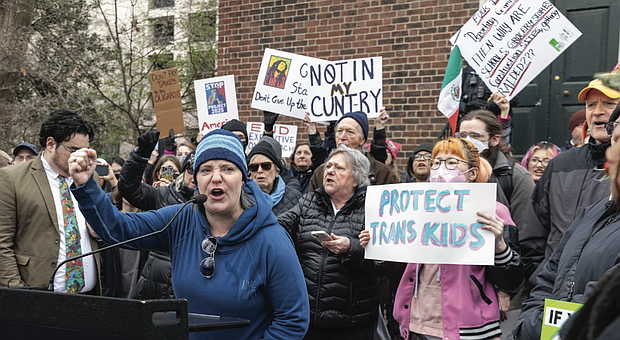 Organizer Kienan Chung stands beside Tess Evans as she speaks to hundreds of protesters at the Bell Tower in Capitol Square on Wednesday, Feb. 5.