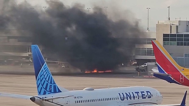 A frame from a video shows flames under a plane and black smoke rising at the Denver airport.
Mandatory Credit:	Courtesy Joshua Sunberg via CNN Newsource