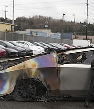 A member of the Seattle Fire Department inspects a burned Tesla Cybertruck in Seattle on March 10.
Mandatory Credit:	Lindsey Wasson/AP via CNN Newsource