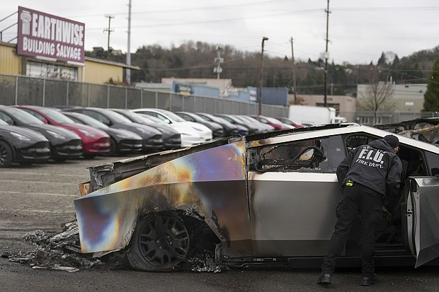 A member of the Seattle Fire Department inspects a burned Tesla Cybertruck in Seattle on March 10.
Mandatory Credit:	Lindsey Wasson/AP via CNN Newsource