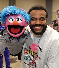 Brandon, a puppet handler for Bob West, the original voice of Barney, greets attendees with a friend from Sesame Street.