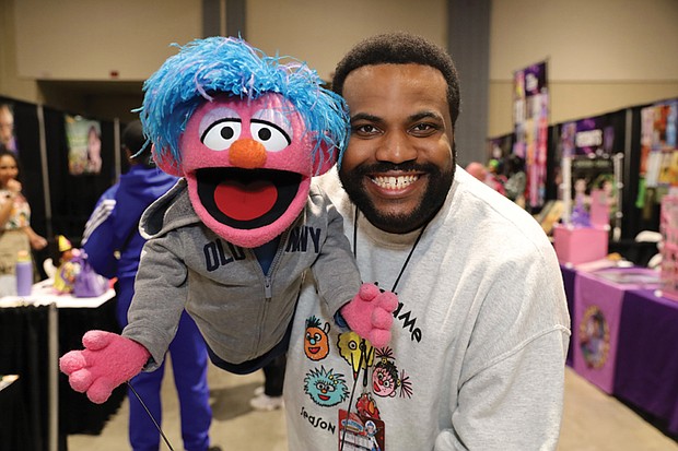 Brandon, a puppet handler for Bob West, the original voice of Barney, greets attendees with a friend from Sesame Street.