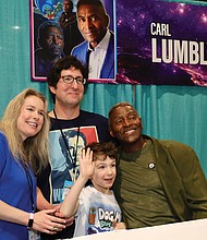 Actor Carl Lumbly poses with fans for a photo at the event.