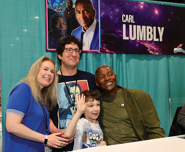 Actor Carl Lumbly poses with fans for a photo at the event.