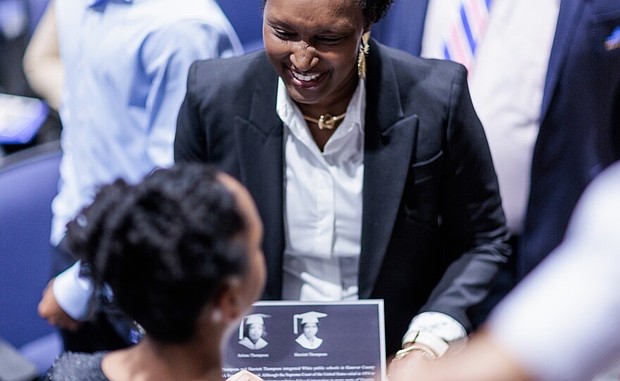 Faizah Hough shows a plaque honoring her mother, Harriett Thompson, to her daughter, Kaylen Hough 12, following a tribute to honor the first students to integrate Patrick Henry High School on Monday, April 14, 2025 in Hanover County. Shaban Athuman / VPM News