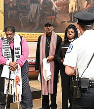 A police officer, right, stands near as the Rev. Jonathan Wilson-Hartgrove, from left, the Rev. William Barber II and others pray in the Capitol Rotunda, Monday, April 28, in Washington.