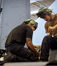 From left, Aviation Structural Mechanic Airman Apprentice Wallace Barnes, from Galveston, Texas, and Aviation Structural Mechanic 2nd Class Aldred Arandia, from Vallejo, California conduct maintenance on an F/A-18E Super Hornet from the “Mighty Shrikes” of Strike Fighter Squadron (VFA) 94 in the hangar bay of the aircraft carrier USS Nimitz (CVN 68) in the Philippine Sea, April 30, 2025.