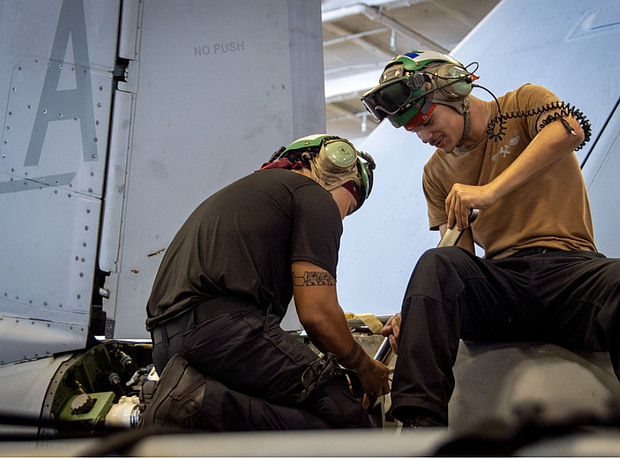 From left, Aviation Structural Mechanic Airman Apprentice Wallace Barnes, from Galveston, Texas, and Aviation Structural Mechanic 2nd Class Aldred Arandia, from Vallejo, California conduct maintenance on an F/A-18E Super Hornet from the “Mighty Shrikes” of Strike Fighter Squadron (VFA) 94 in the hangar bay of the aircraft carrier USS Nimitz (CVN 68) in the Philippine Sea, April 30, 2025.