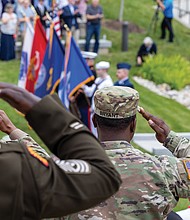 Military service members salute during the presentation of the colors at the Virginia War Memorial during the Memorial Day ceremony.