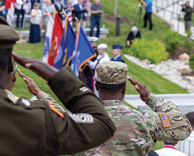 Military service members salute during the presentation of the colors at the Virginia War Memorial during the Memorial Day ceremony.