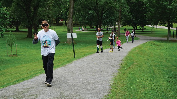 Nidal Mahayni raises a peace sign while walking the Vita Course Trail in Byrd Park during Saturday’s walkathon supporting mental health care for children in Gaza.
