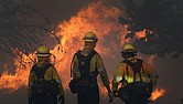 Members of a Los Angeles County Fire crew make a stand to protect a home from advancing fire on Sept. 18, 2020, in Juniper Hills, Calif.