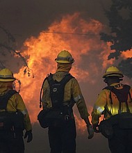 Members of a Los Angeles County Fire crew make a stand to protect a home from advancing fire on Sept. 18, 2020, in Juniper Hills, Calif.