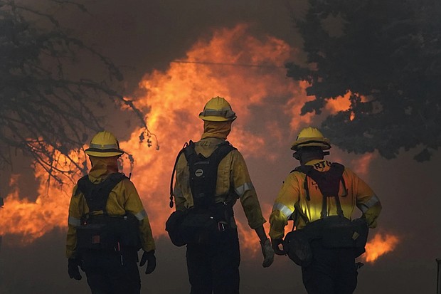 Members of a Los Angeles County Fire crew make a stand to protect a home from advancing fire on Sept. 18, 2020, in Juniper Hills, Calif.